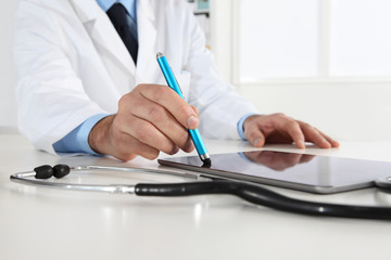 doctor hand touch screen of digital tablet writing prescription at desk in medical office close up