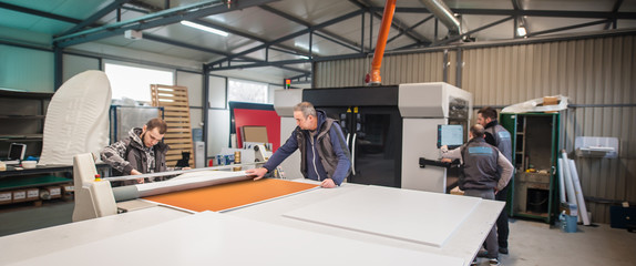 Large group of technicians works in printing printshop press hall