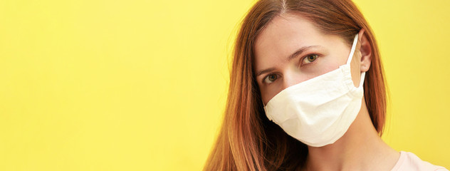 Wall Mural - Young woman in white home made cotton face virus mask, wide banner with yellow background, space for text left side. Coronavirus covid-19 outbreak prevention concept