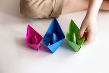 Child Plays With Colored Paper Boats