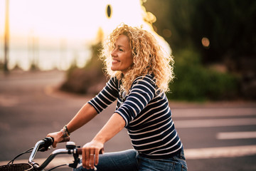 cheerful beauiful blonde curly caucasian woman smile and enjoy the ride on a bike in outdoor leisure