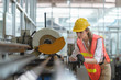 Female worker with safety vest and yellow helmet working in line production at a factory Industrial