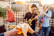 © beavera - Friends making a toast at a live concert in a rooftop in summer time. Young people holding cups of lager beer and cheering. Leisure and music concept. Happy people having fun while drinking beer.