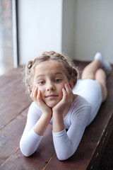 a charming little girl in a white gymnastic costume is training in rhythmic gymnastics. a little gir