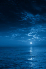Wall Mural - this photo illustration of a deep blue moonlit ocean and sky at night would make a great travel back