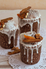 Vertical photo of stylish traditional Orthodox Easter delicious cake and two others on the background on the white napkins decorated by dried bananas, orange apricots, almonds and sugar silver beads