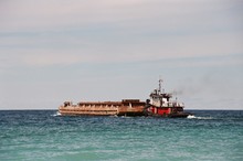 Tugboat Pushing Barge On Sea Against Sky