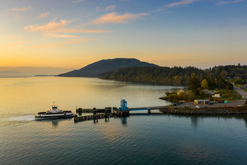 Wall Mural - Aerial View of a Ferry Boat Landing at the Island Dock. Aerial shot of a small 21 car ferry landing at the Lummi Island ferry dock on a beautiful sunlit morning in the the Pacific Northwest, USA.