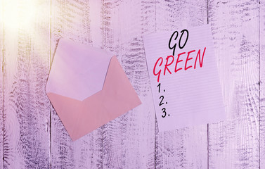 Handwriting text Go Green. Conceptual photo making more environmentally friendly decisions as reduce recycle Front view open colored envelope blank sheet letter paper wooden background