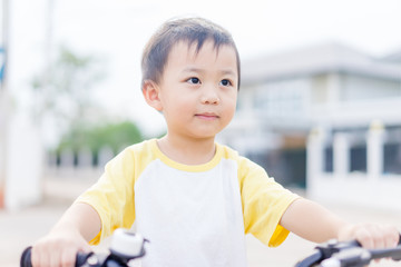 Wall Mural - 3 years old happy toddler asian boy child ride bike in street at home village .boy ride bicycle to play at playground : Healthy happy funny smiling face young adorable lovely boy child kid at home.