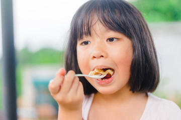 Wall Mural - Thai kid little girl eat roti sweet dessert very famous in Thailand.Hungry face and enjoy eating concept.Little asian girl enjoy eating with Homemade fresh wheat flour Chapati.