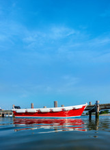 Boats Docked At A Marina With Wooden Pear Simple Red Rowing Boat As The Main Subject