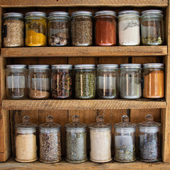 Glass reusable spice jars in a rustic wooden cabinet