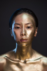 Wall Mural - Portrait of young asian woman in golden paint