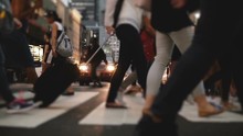 Low Angle Slow Motion Shot Of People's Legs And Feet Walking Across A Busy City Street Near Times Square In The Evening.