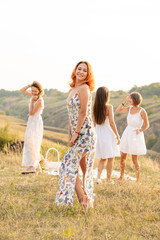 Wall Mural - The company of happy female friends having fun and dancing outside in a picnic at hills.