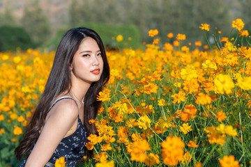 Wall Mural - asian cute young woman joyful, smiling with yellow cosmos background.