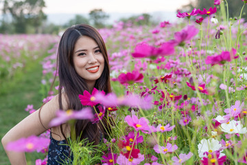 asian cute young woman joyful, smiling with pink cosmos background.