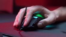Gaming Device Mouse. A gamer is playing in a computer club. In the frame, the hand of a gamer and a gaming mouse. Red and violet colors. ESports competitions.

