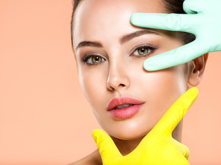 Face skin check before plastic surgery. Beautician touching young woman face. Doctor in medicine gloves checks a skin before plastic surgery. Beauty treatments.