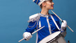 © Ulia Koltyrina - Charming cheerful drummer in a blue uniform, sings and plays the drum.