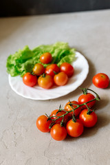 Wall Mural - Cherry tomatoes with lettuce on a gray background
