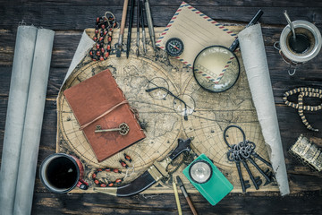 Aufkleber - Preparing for travel.  Great adventure planning concept.  Retro style.  Old maps, expedition accessories.  Notebook, magnifier, flashlight, compass, tea cup, treasure chest and key on a wooden bench