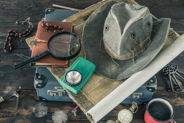 Aufkleber - Preparing for travel.  Great adventure planning concept.  Retro style.  Old maps, expedition accessories.  suitcase, notebook, magnifier, flashlight, compass, tea cup, hat on a wooden bench