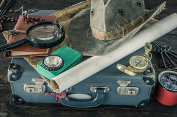 Aufkleber - Preparing for travel.  Great adventure planning concept.  Retro style.  Old maps, expedition accessories.  suitcase, notebook, magnifier, flashlight, compass, tea cup, hat on a wooden bench