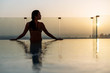 © matilda553 - Woman relaxing in infinity pool with sunset city view. Relaxing vacation.  Dubai UAE