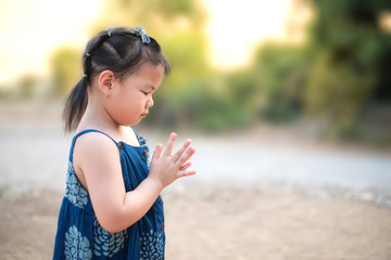 A cute little Asian girl prayed to God in the morning. The concept of prayer for faith, spirit, and religion