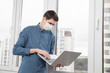 © makedonski2015 - A guy in a protective face mask works at a computer from home during a virus epidemic. Quarantine during viral infection
