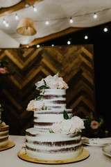 A beautiful naked wedding cake decorated with flowers.