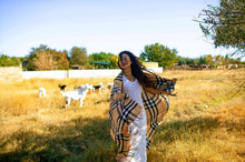 Young Happy Lady Among Sheeps In The Field At Countryside.