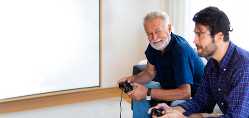 Wall Mural - Father and son family time together at home concept. Happy father and son enjoy playing video games with joysticks in living room at home