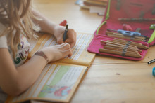 Young Blonde Left-handed Girl Is Writing In A Workbook To Train Her Handwriting At Home - Homeschooling Concept