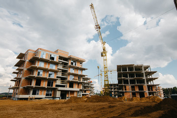 
construction site of residential buildings with cranes in sunny weather with blue sky