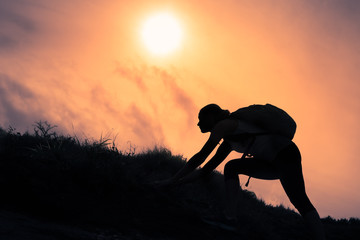 Female silhouette climbing up a mountain path.  People mental strength and determination. 