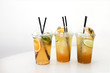 three lemonades, ice tea, on white table in plastic cups, take away, food delivery