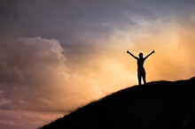 Happy Female Standing On A Hill Facing The Sunset Putting Her Arms, Thumbs Up Feeling Happy, Energized, And Free. Finding You Inner Strength Concept. 