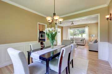 Classic elegant mustard color and grey tones dining room with large table and linen chairs.