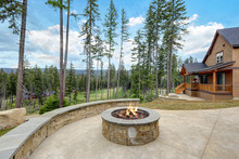 Stone Patio With Fire Pit And Large Stone Wall With Sitting Space.