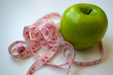 Green apple and tape measure in centimetrs as symbol of diet before summer time and healthy lifestyle