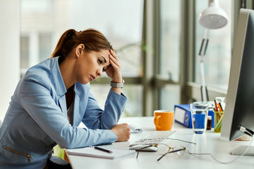 Wall Mural - Young distraught businesswoman thinking while sitting at her office desk.