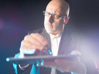 Poster - A man with glasses is holding an electronic tablet and a stylus. Computer gadgets. Modern communication technologies. Getting information from the Internet. Making orders online.