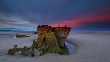 Wall Mural - Shipwrecked off the coast of Ireland, An shipwreck or abandoned shipwreck,,boat Wreck Sunset light at the beach, Wrecked boat abandoned stand on beach or Shipwreck