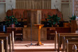 medium wide shot of an empty church sanctuary with afternoon sunlight pouring in creating shadows down the aisle to the front of the church 