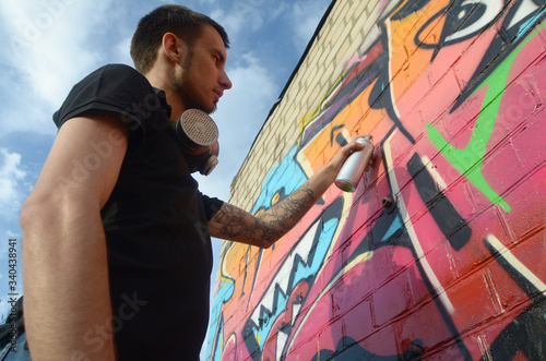 Young Graffiti Artist With Backpack And Gas Mask On His Neck Paints Colorful Graffiti In Pink Tones On Brick Wall Street Art And Contemporary Painting Process Stock Photo Adobe Stock