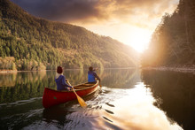 Couple Friends Canoeing On A Wooden Canoe During A Colorful Sunny Sunset. Cloudy Sky Composite. Taken In Harrison River, East Of Vancouver, British Columbia, Canada.