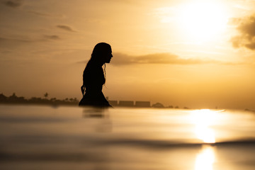 Wall Mural - silhouette of a woman surfing in the ocean